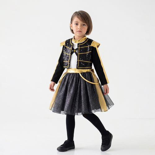 Niña de cuerpo entero con atuendo negro de detalles dorados, chaqueta corta y falda amplia, sobre un fondo blanco.