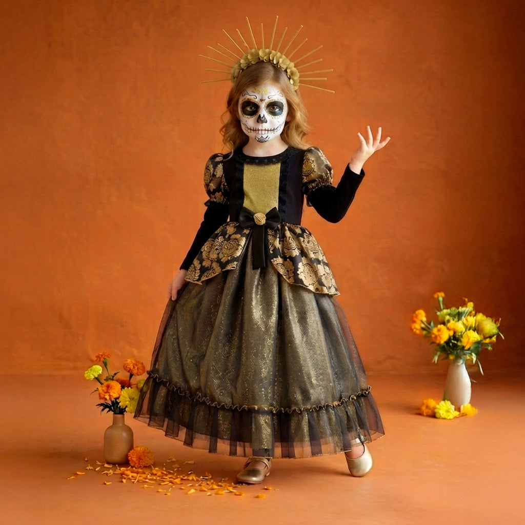 Niña con maquillaje de calavera y vestido largo negro y dorado, frente a un fondo naranja con flores.
