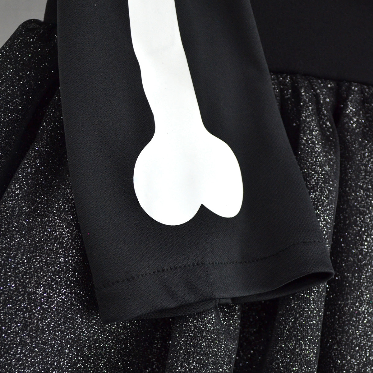 Detalle de la manga negra del vestido de esqueleto, con estampado de hueso blanco junto a la falda de tul brillante.