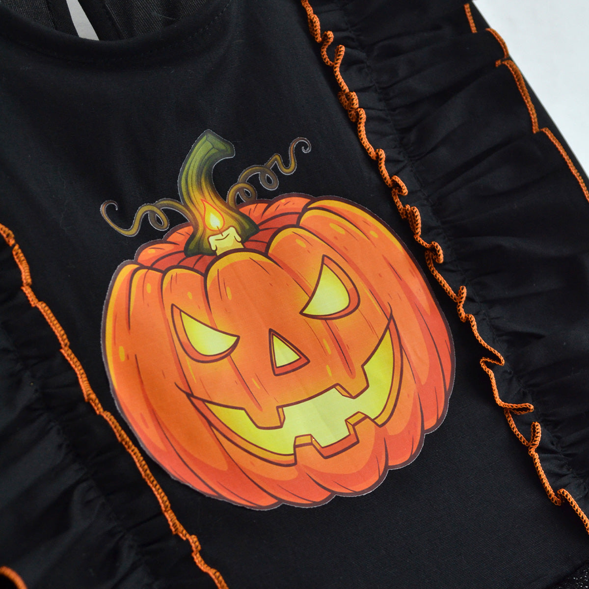 Detalle del estampado de calabaza naranja de Halloween sobre el corpiño negro, con volantes de ribete naranja.