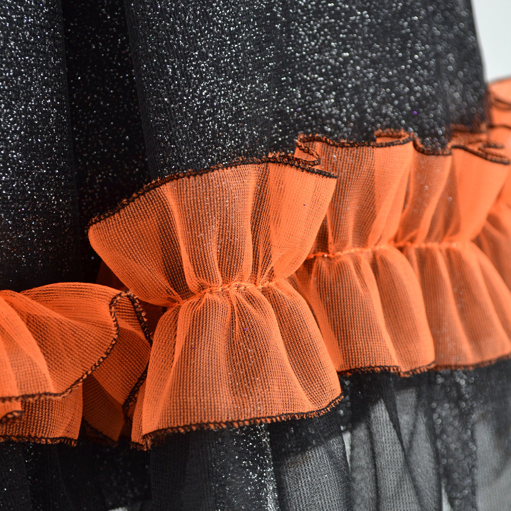 Detalle de la falda negra brillante con olán de tul naranja fruncido y bordes negros.