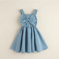 Vestido infantil azul celeste con tirantes anchos, gran moño al frente y falda amplia fruncida, sobre fondo beige.