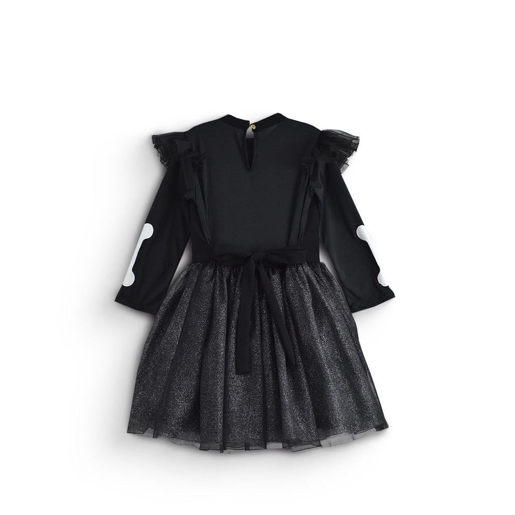 Vista trasera de vestido infantil negro de esqueleto, con mangas largas, volantes en los hombros y falda de tul brillante.