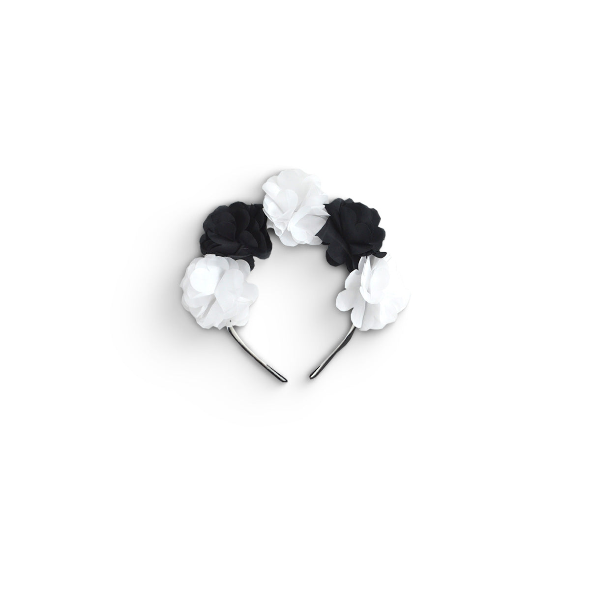 Diadema negra decorada con flores blancas y negras, sobre fondo blanco.