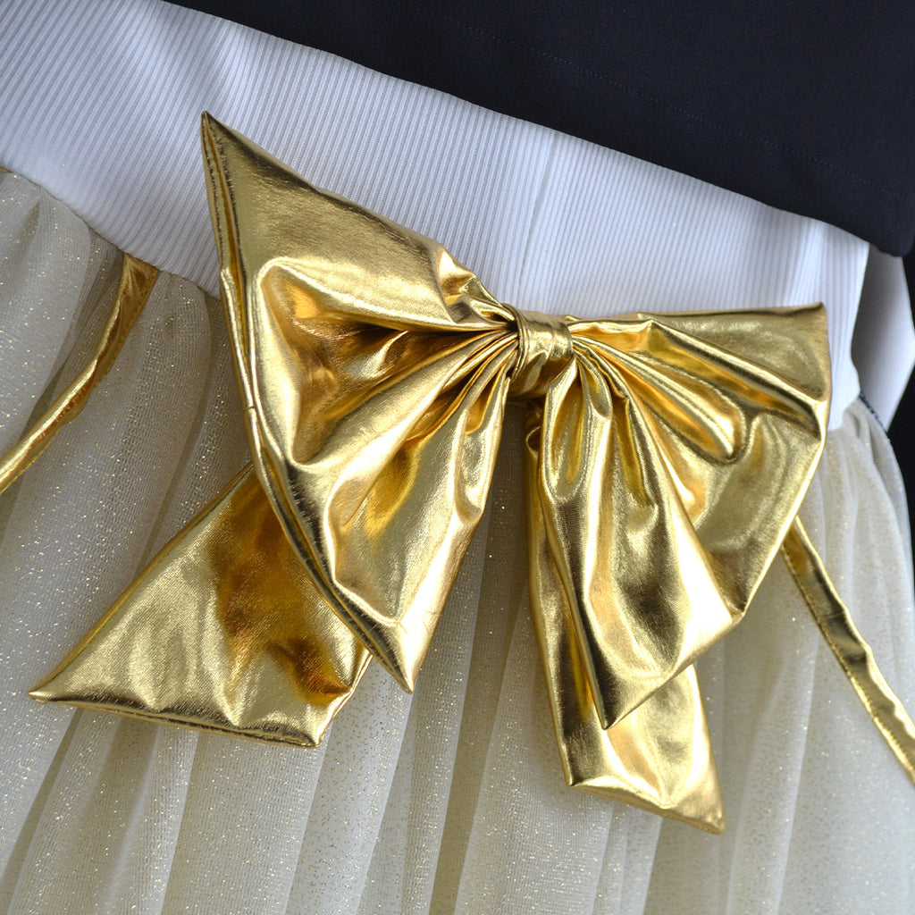 Detalle del gran moño dorado en la cintura del vestido color marfil, sobre la falda de tul.