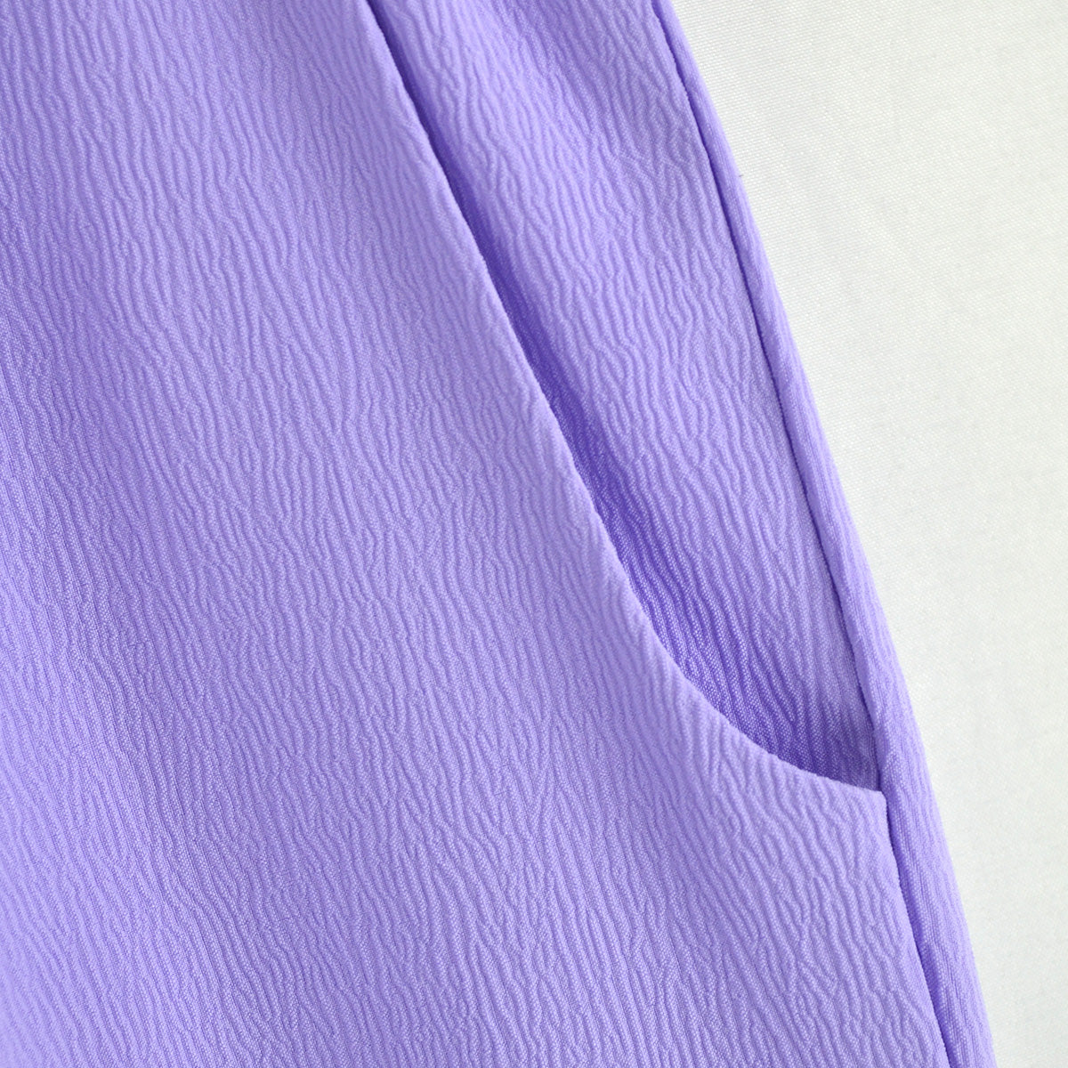Detalle del bolsillo lateral y la textura de la tela del pantalón infantil lila.
