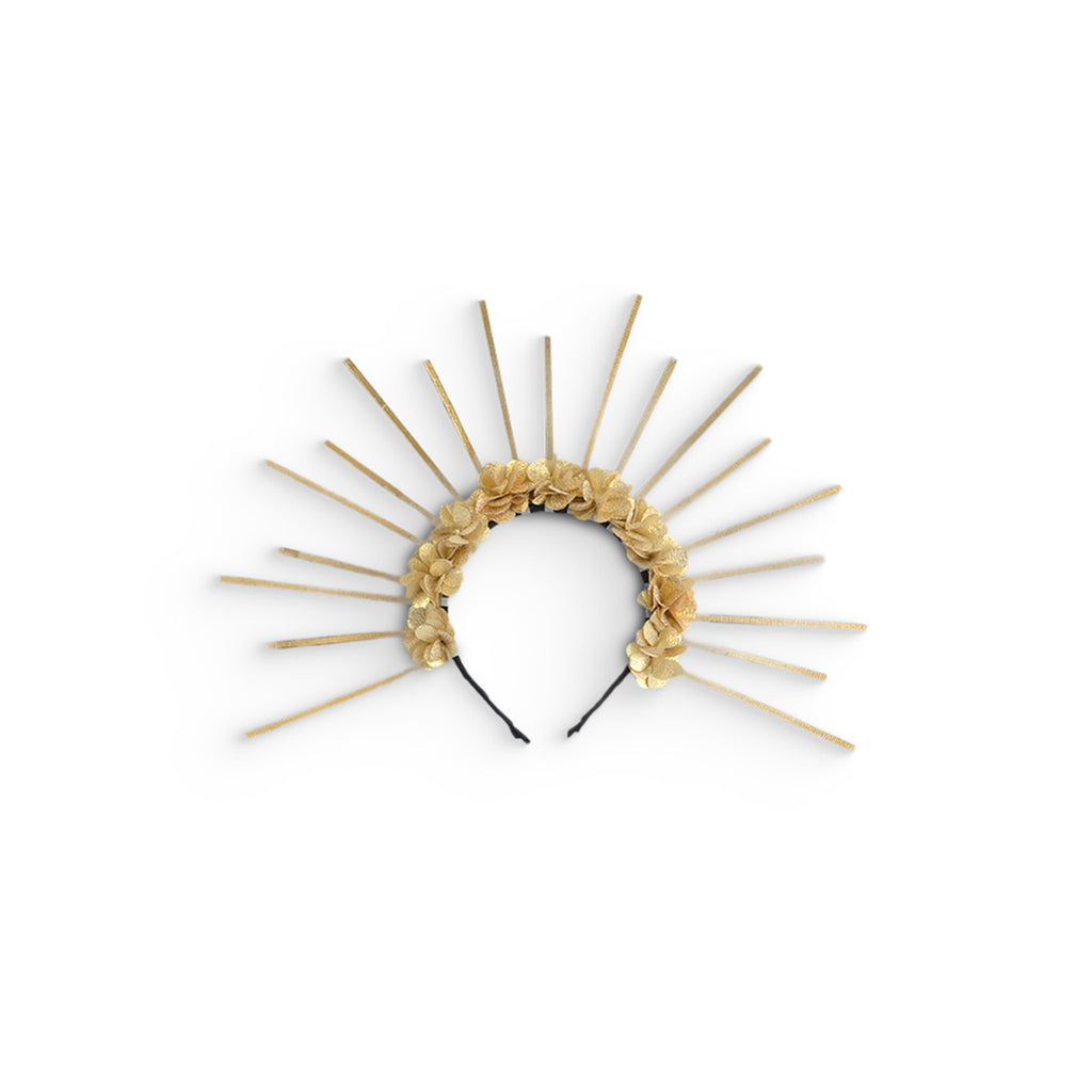 Diadema decorada con flores doradas y varillas en forma de rayos, sobre fondo blanco.