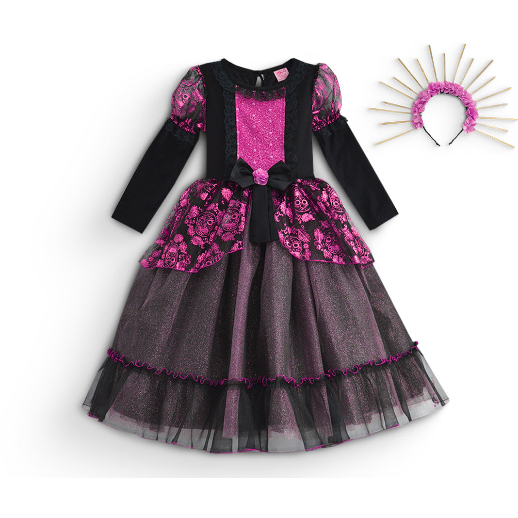 Vestido infantil negro y fucsia de manga larga, con estampado de calaveras, lazo en la cintura y falda de tul en capas, junto a una diadema de flores rosas y rayos.