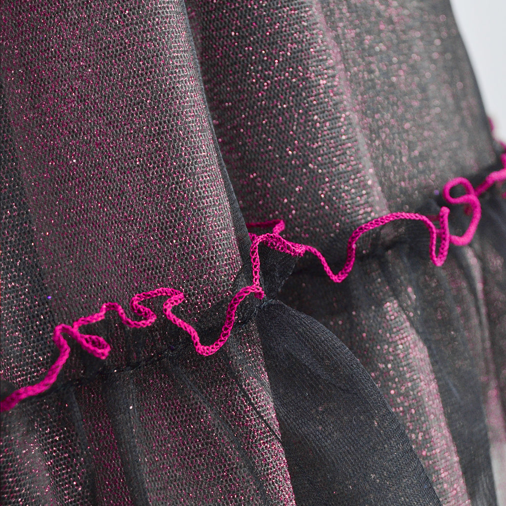 Detalle de la falda de tul negro brillante con ribete ondulado color fucsia.