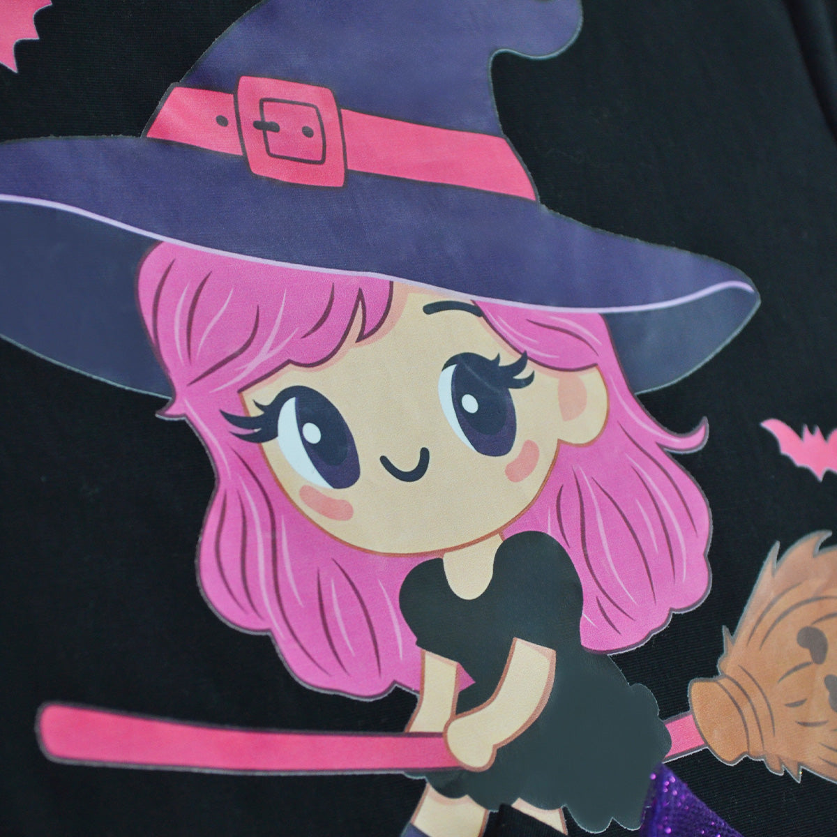 Detalle del estampado de una brujita de cabello rosa con sombrero y escoba.